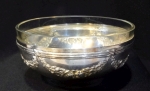 Bowl francês em metal espessurado à prata com guirlandas de flores e bordas em frisos, tendo um cristal em seu interior. Diâmetro de 9 cm e altura de 4,5 cm.