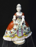 Escultura européia de dama antiga segurando leque e veste vermelha e ricos detalhes de renda com rosas e laços amarelos. Possui marca e assinatura na base. Altura de 14 cm.