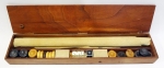 Gamão - jogo composto de caixa em madeira, tabuleiro em pele de napa estampada, contendo 26 pedras em madeira (clara e escura), 3 dados brancos e um maior negro, com números.