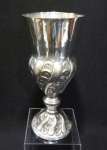Vaso em metal espessurado à prata cinzelada com detalhes de gomos e flores. Altura de 27 cm.