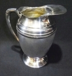 Wolff - jarra para água em metal espessurado à prata c/ alça bojuda com friso no corpo tipo corrente. Tem aparador de gelo na borda. Altura de 18 cm.