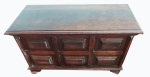 Baú retangular com frente em almofadas em relevo de madeira escura e tampo liso, com desgastes do uso.  Mede 95 x 45 e altura de 50 cm.