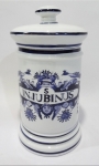 Pote de farmácia em porcelana opalinada com inscrição "Injubinus" e desenhos de pássaro e anjo. Tampa filetada com frisos cor azul cobalto. Altura de 24 cm.