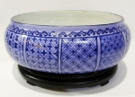 Belo centro de mesa em porcelana com desenhos geométricos na cor azul royal e ao centro,  a figura de dragão. Acompanha base em madeira escura entalhada. Altura de 15 cm e medidas, 32 x 24 cm.