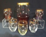 Jogo para drink em demi cristal na cor rosè degradê com pequenas flores brancas e bordas douradas. A vasilha de preparo mede 20 cm e os copos com 8 cm.