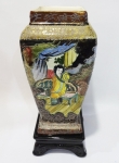 Vaso de porcelana em estilo japonês decorado em relevos de queixas e samurais em jardins tendo base em cerâmica negra. Altura de 34 cm.